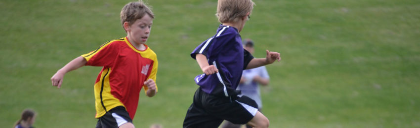 photo of Two boys running and playing soccer