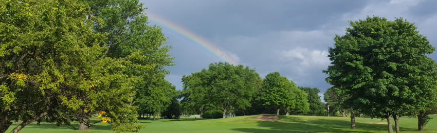 Photo of Apple Orchard Golf Course Rainbow in cloudy sky over trees