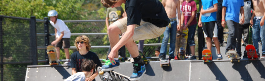 photo of Teens riding skate boards at skate park
